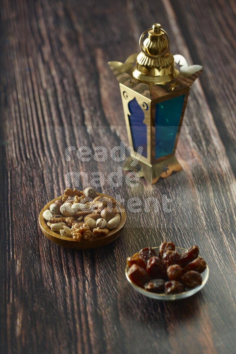 A golden lantern with different drinks, dates, nuts, prayer beads and quran on brown wooden background