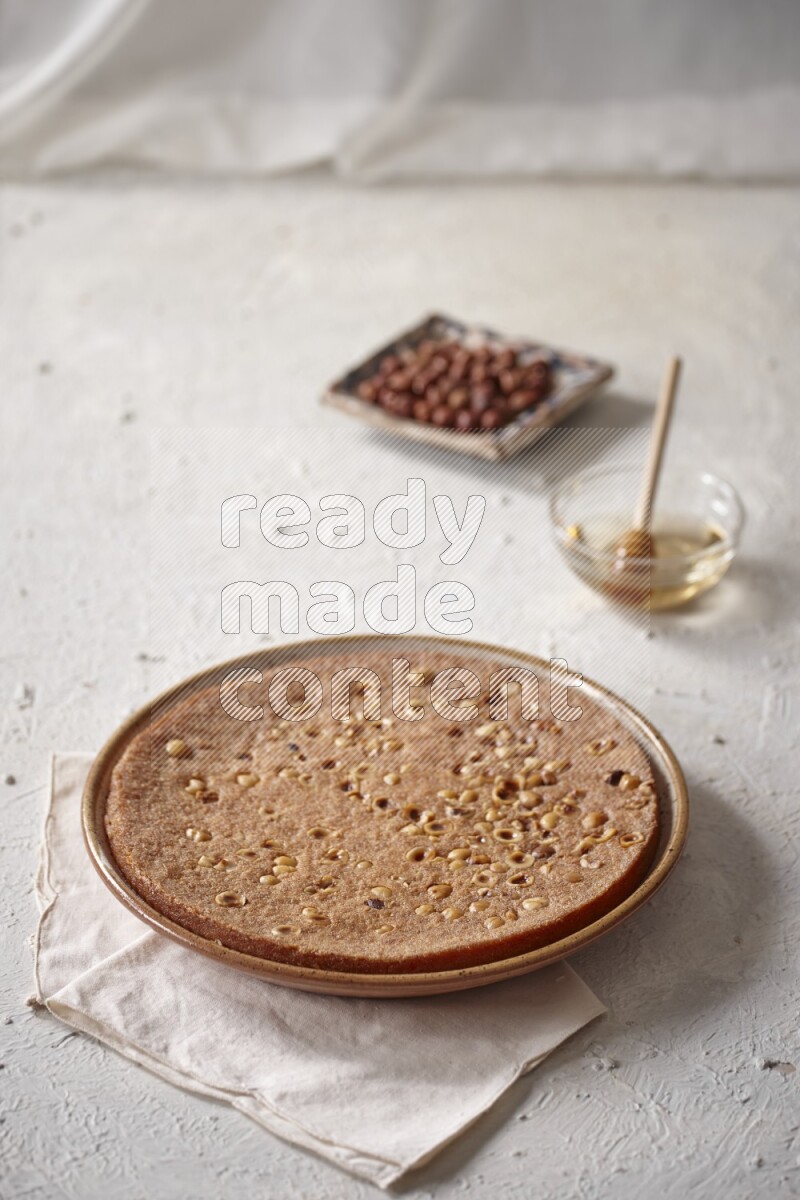 البسبوسة مع المكسرات والعسل علي خلفية بيضاء خشبية