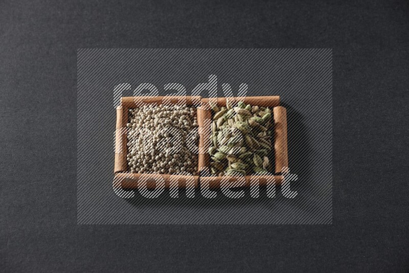 2 squares of cinnamon sticks full of white peppers and cardamom on black flooring