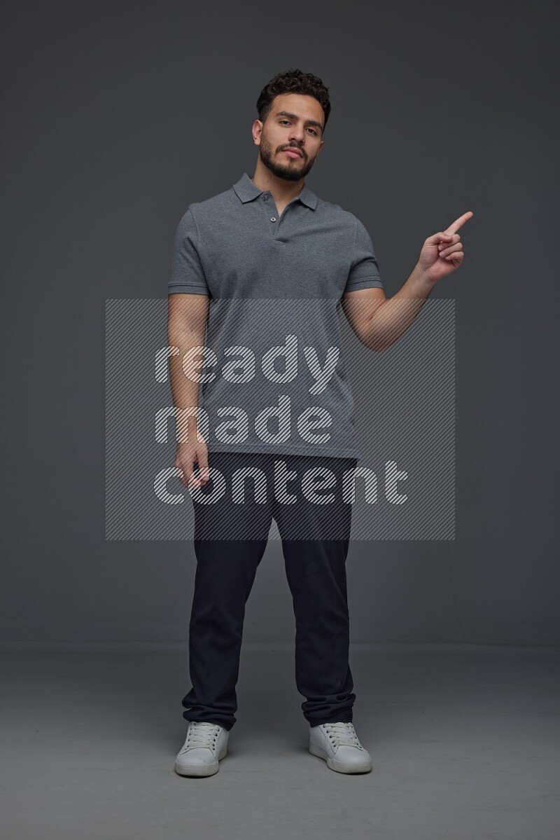 A man wearing casual standing and making multi hand gestures eye level on a gray background