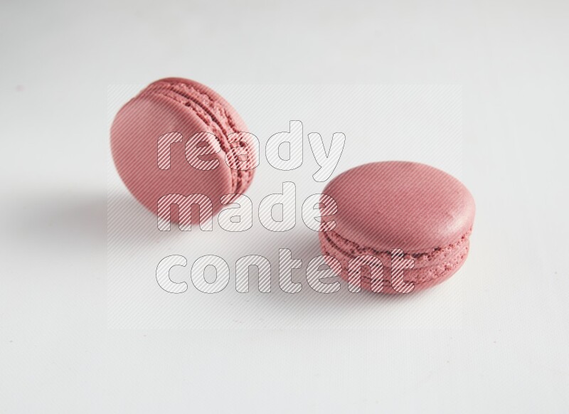 45º Shot of two Pink Raspberry macarons on white background