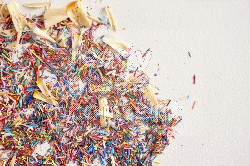 This image showcases a vibrant multicolored pencil shavings scattered on grey background