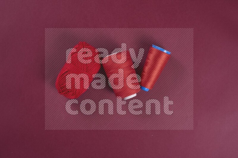 مجموعة من أدوات الخياطة والتفصيل حمراء اللون على خلفية حمراء