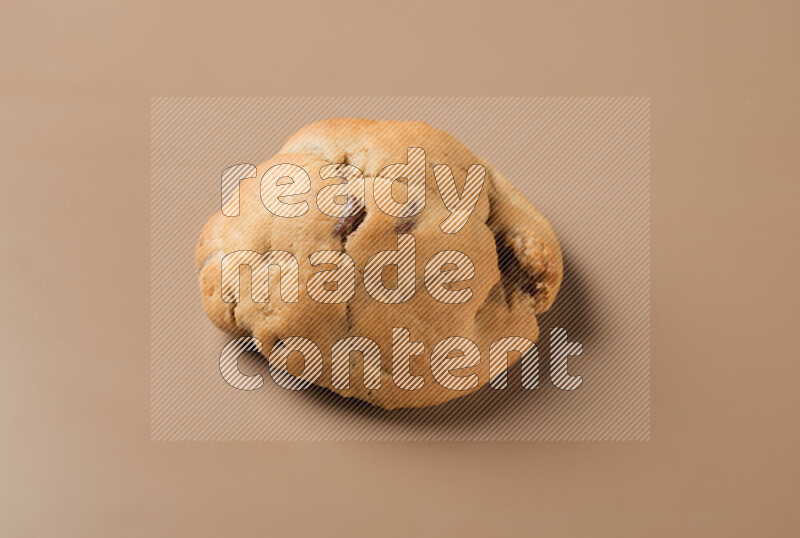 a whole chocolate chip cookie on a brown background