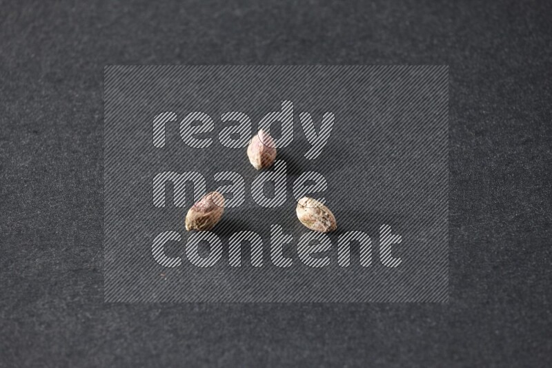 3 peeled pistachios on a black background in different angles