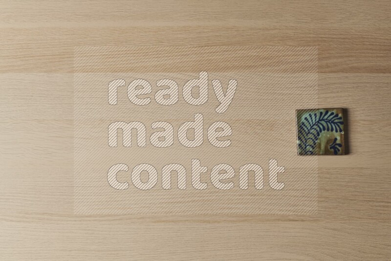 A decorative pottery coaster on light wooden background