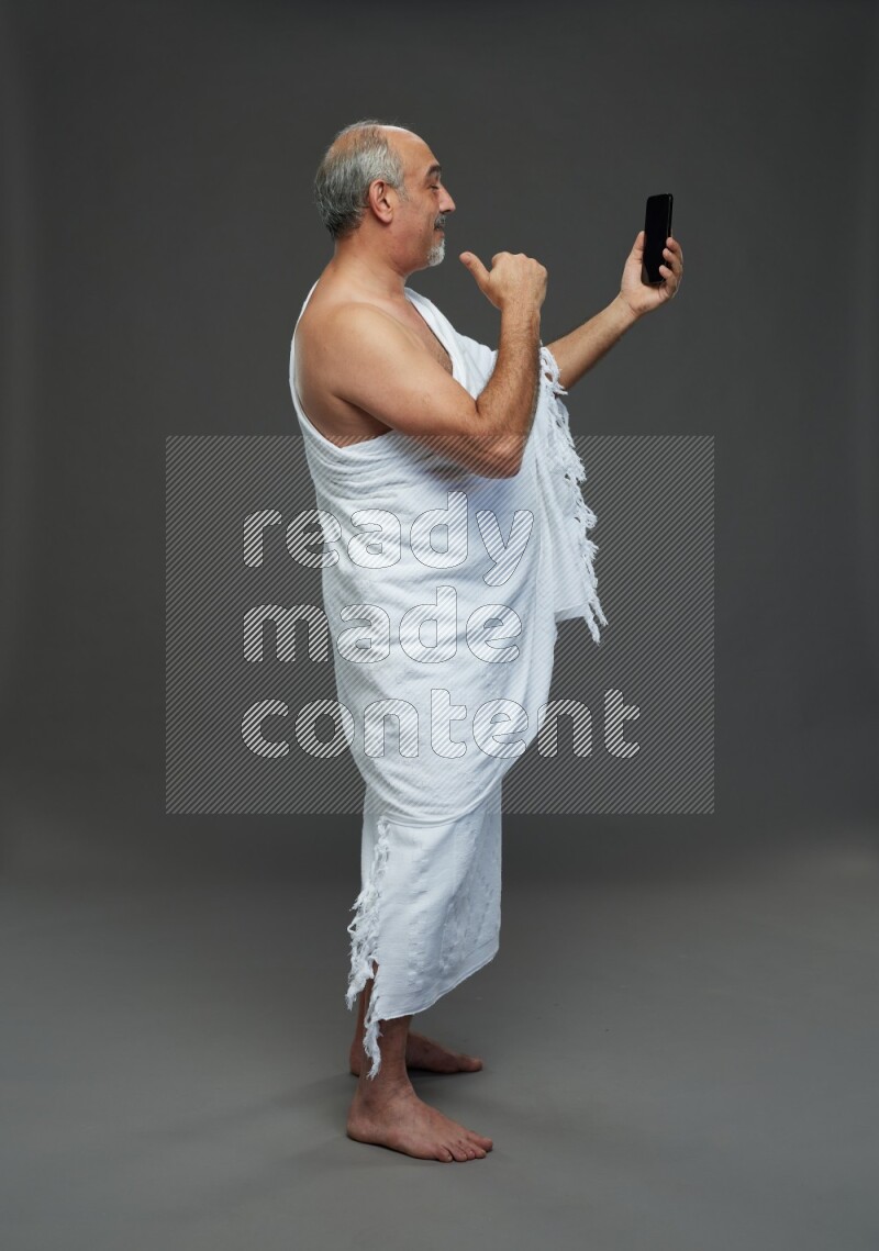 A man wearing Ehram Standing taking selfie on gray background