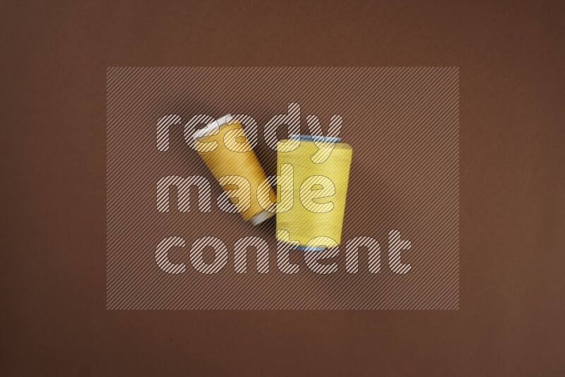 A yellow collection of sewing and tailoring tools arranged on a brown background