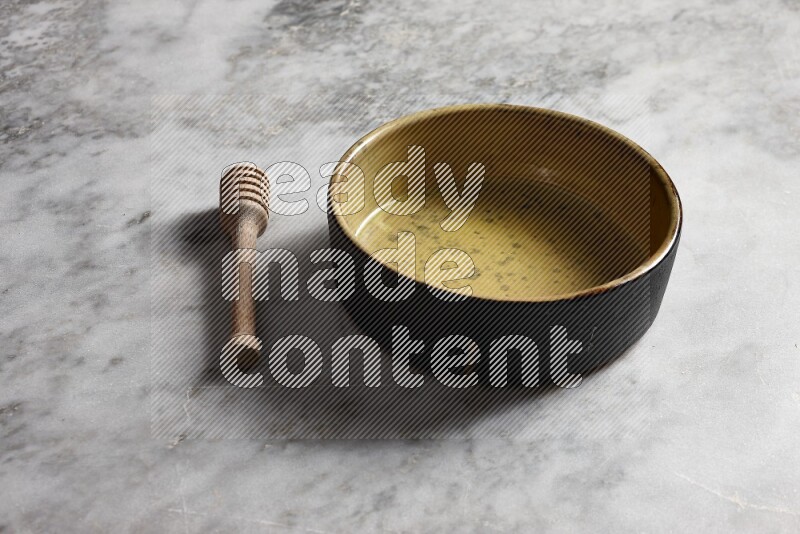 Multicolored pottery oven plate with wooden honey dipper on the side on grey marble background