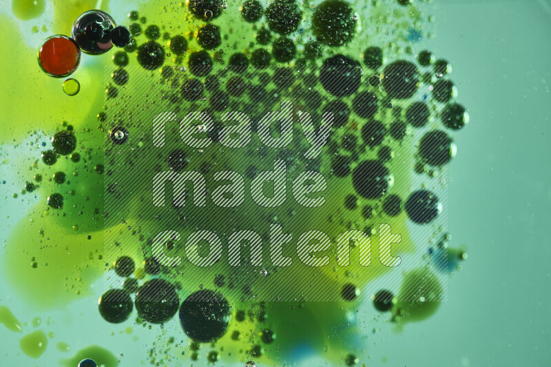 Close-ups of abstract red, green and yellow watercolor drops on oil Surface on green background