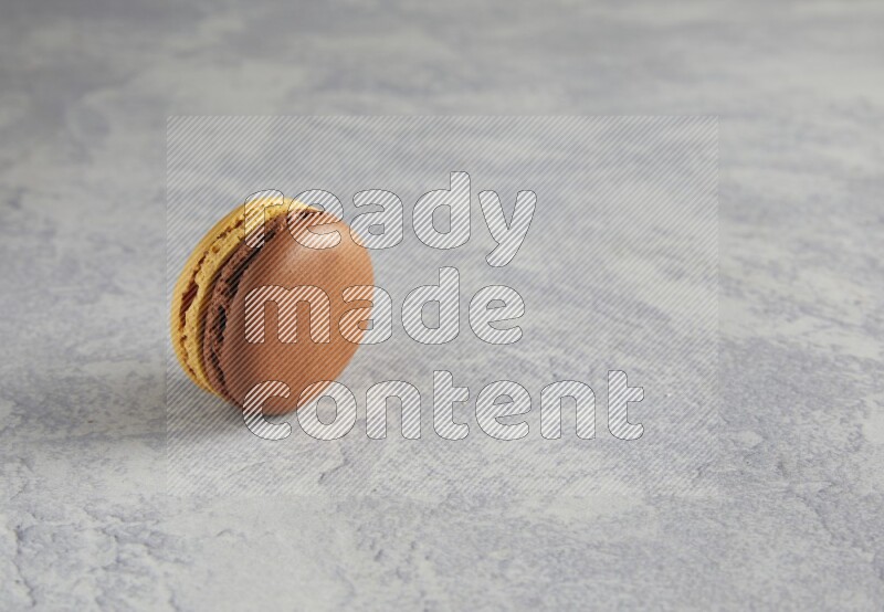 45º Shot of Yellow and Brown Chai Latte macaron on white  marble background