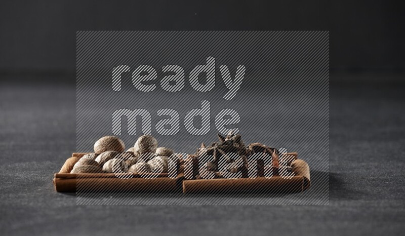 2 squares of cinnamon sticks full of nutmeg and star anise on black flooring