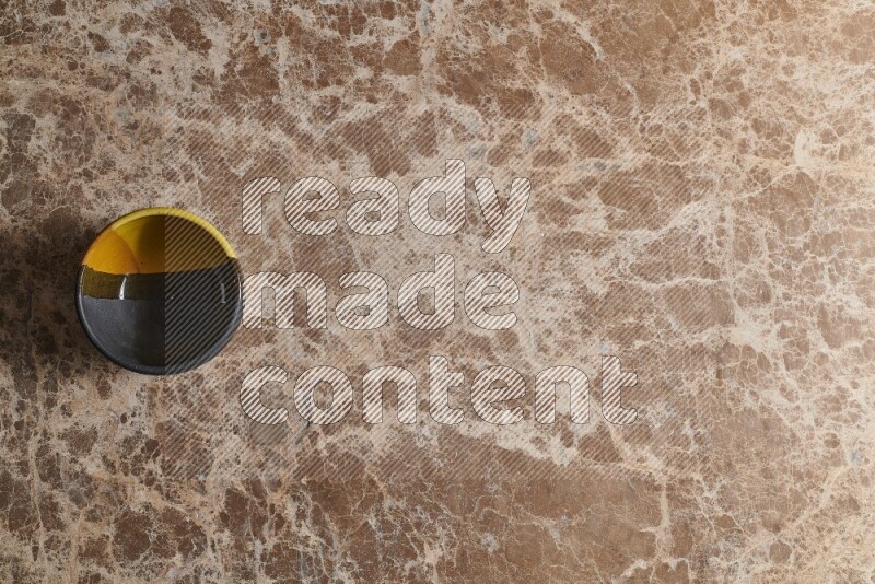 A multicolored pottery bowl on beige marble background