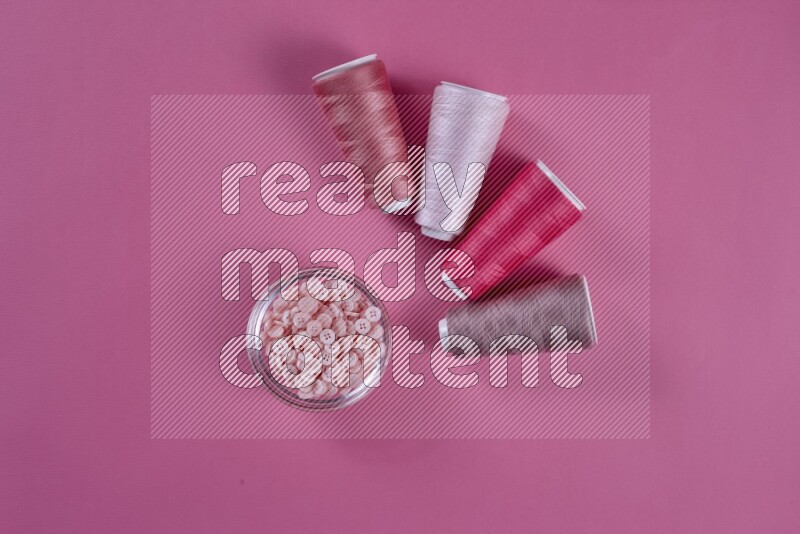 A pink collection of sewing and tailoring tools arranged on a pink background