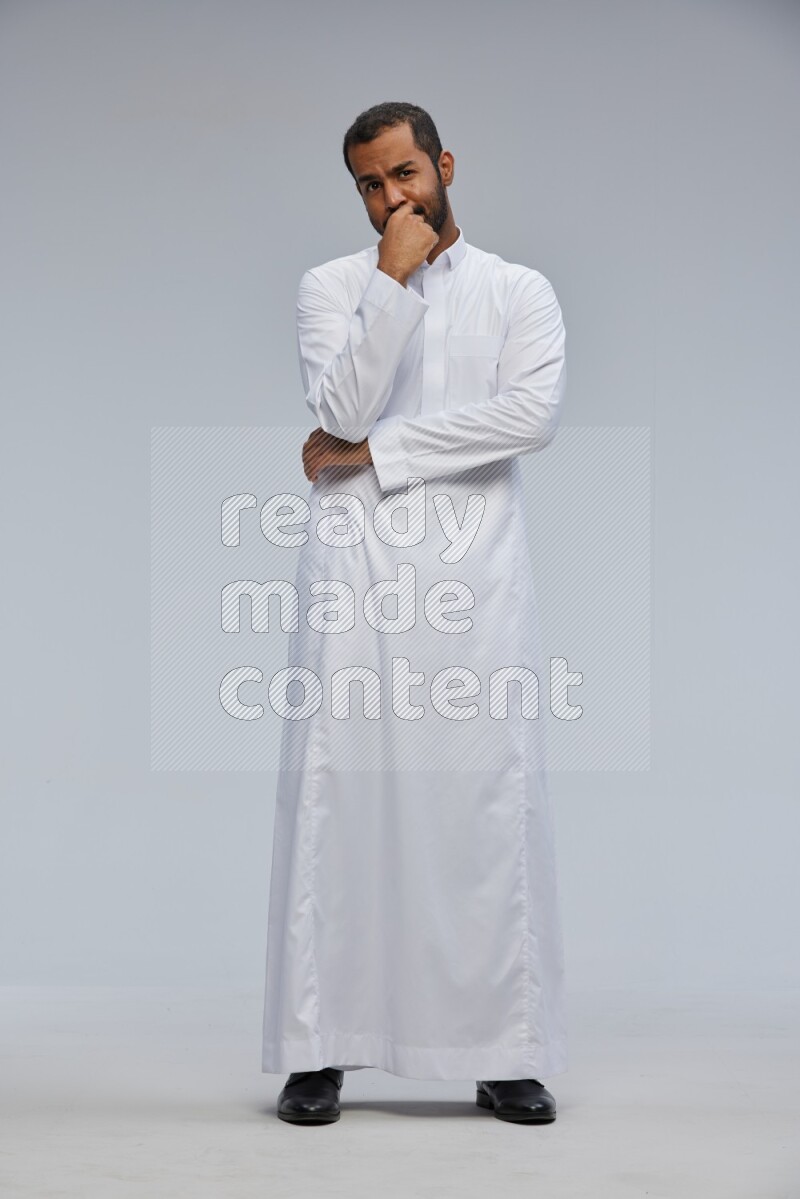Saudi man Wearing Thob standing interacting with the camera on Gray background