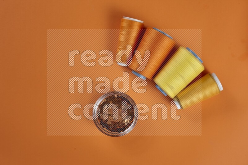 A yellow collection of sewing and tailoring tools arranged on a orange background