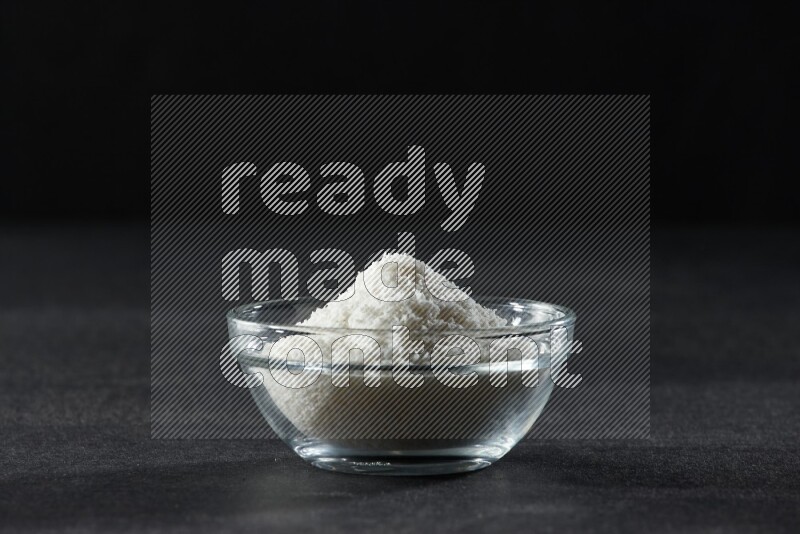 وعاء زجاجي ممتلئ بجوز الهند المجفف المبشورعلى خلفية سوداء