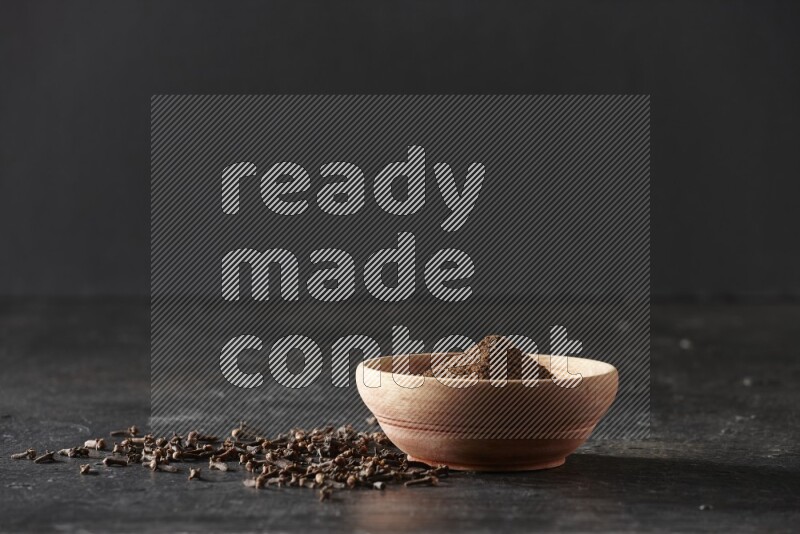 وعاء خشبي ممتلئ ببودرة القرنفل علي خلفية سوداء