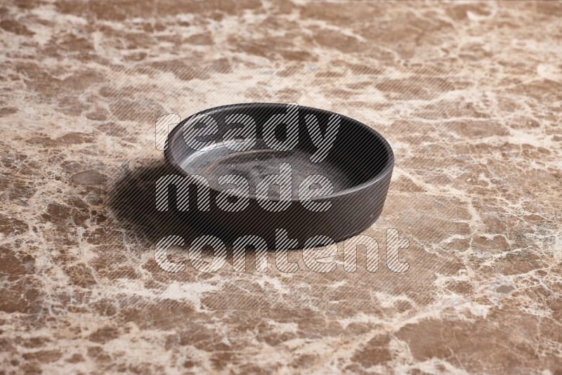 A black pottery oven plate on beige marble background