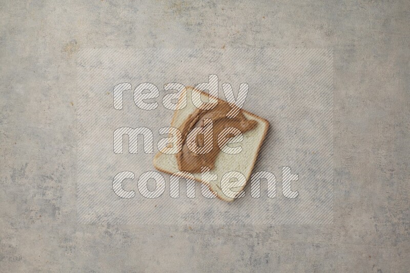 Creamy peanut butter on a white toast on a light blue textured background