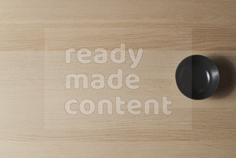 وعاء سيراميكي أسود على خلفية خشبية فاتحة