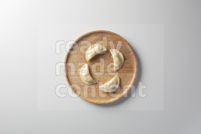 Four Sambosas on a wooden round plate on a white background