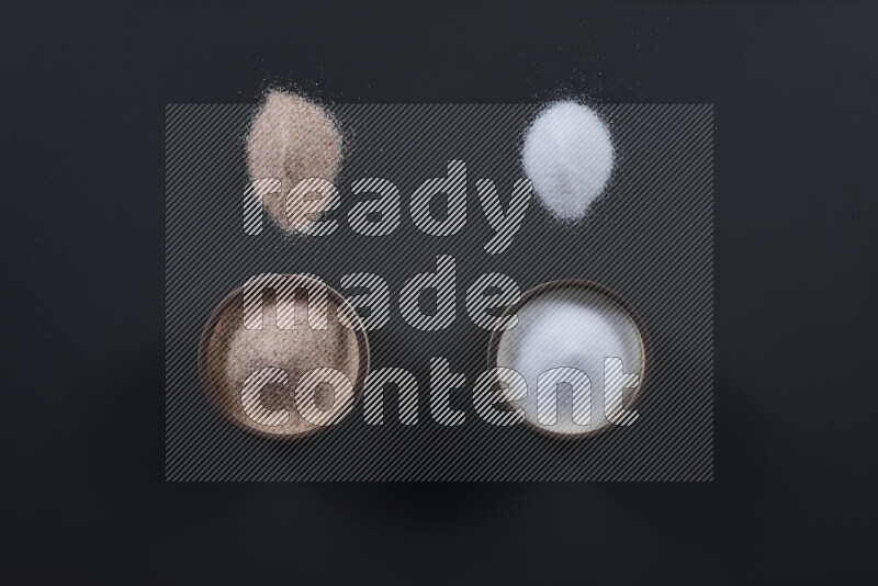 2 وعاء فخاري احدهمها ممتلئ بملح الهيمالايا والأخر بالملح الأبيض على خلفية سوداء