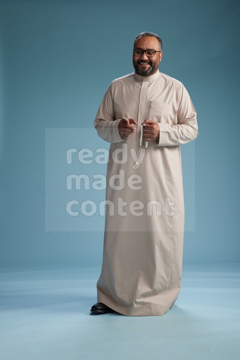 Saudi Man without shimag Standing Interacting with the camera on blue background