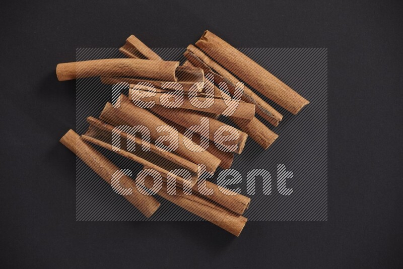 Cinnamon sticks stacked on black flooring
