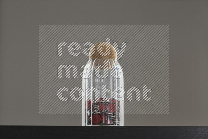 أزرار متنوعة في وعاء زجاجي علي خلفية سوداء