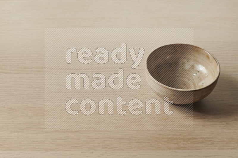 A beige pottery bowl on light wooden background