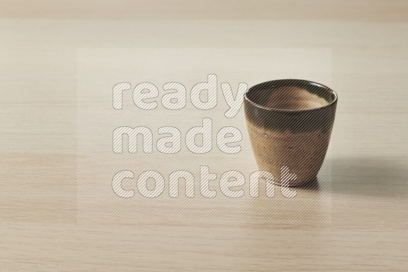 A pottery cup on light wooden background