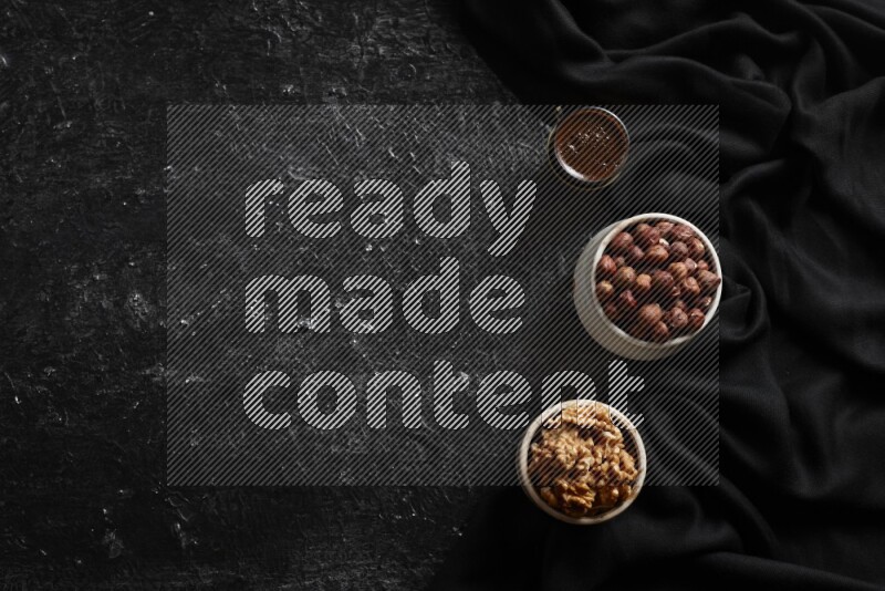 Nuts in pottery bowls with coffee in a dark setup