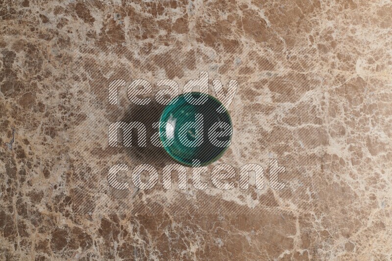 A dark green pottery bowl on beige marble background