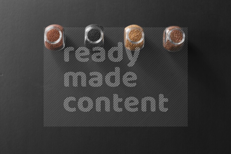 4 glass spice jars full of black seeds, mustard seeds, flax and garden cress on black flooring