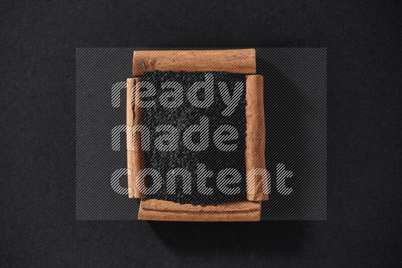 A single square of cinnamon sticks full of black seeds on black flooring