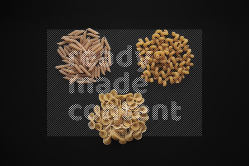 Different pasta types in bunches on black background