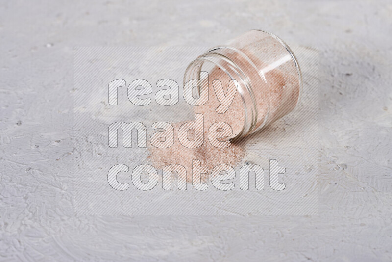 A glass jar full of fine himalayan salt on white background