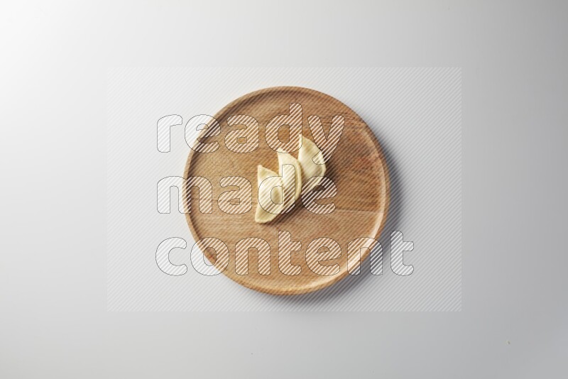 Three Sambosas on a wooden round plate on a white background