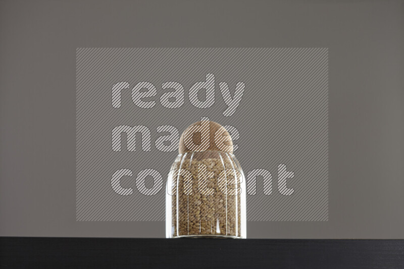 Hulled wheat in a glass jar on black background