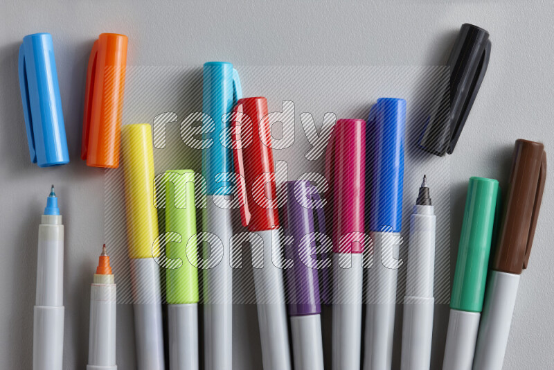 An arrangement of coloring pens in different colors on grey background