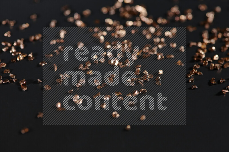 قطع زجاجية برونزية لامعة متناثرة على خلفية سوداء