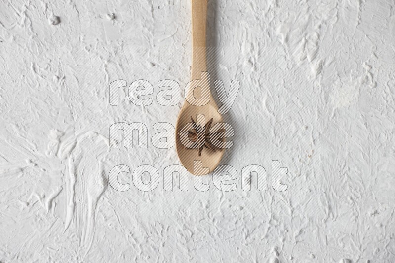 Star Anise in a wooden spoon on white flooring