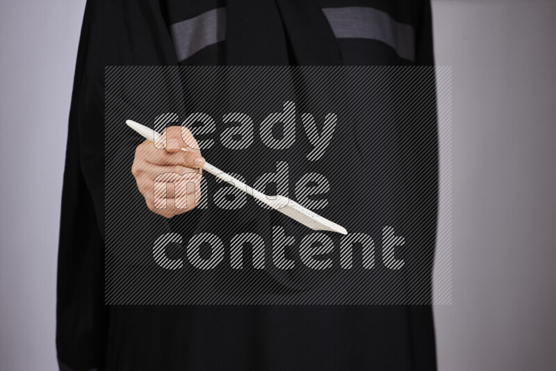 A woman in black abaya holding different wooden essentials in different positions