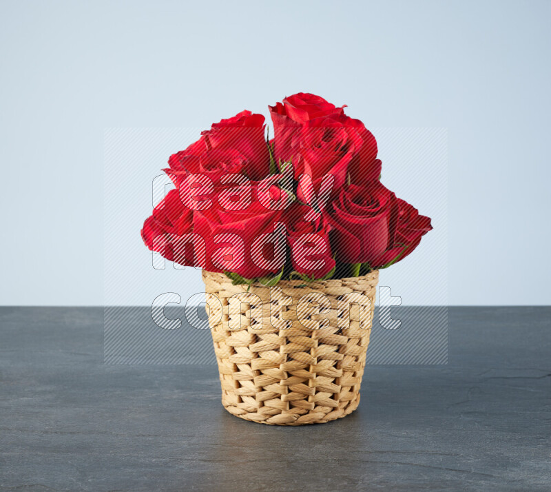 Vibrant red roses in a wicker basket on black marble background