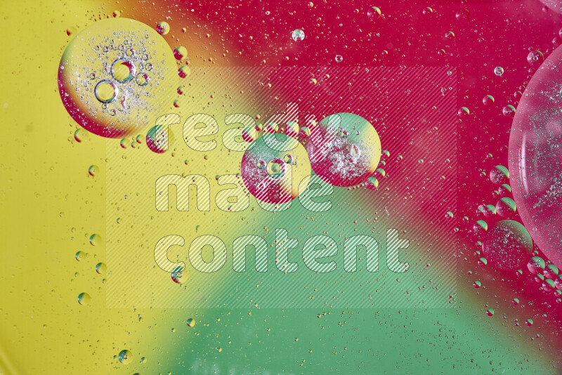 Close-ups of abstract oil bubbles on water surface in shades of yellow, green and red