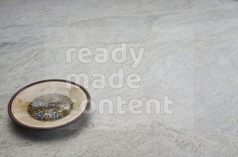 A decorative pottery plate on grey marble background