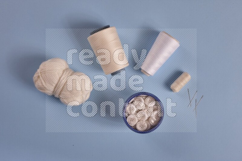 A white collection of sewing and tailoring tools arranged on a blue background