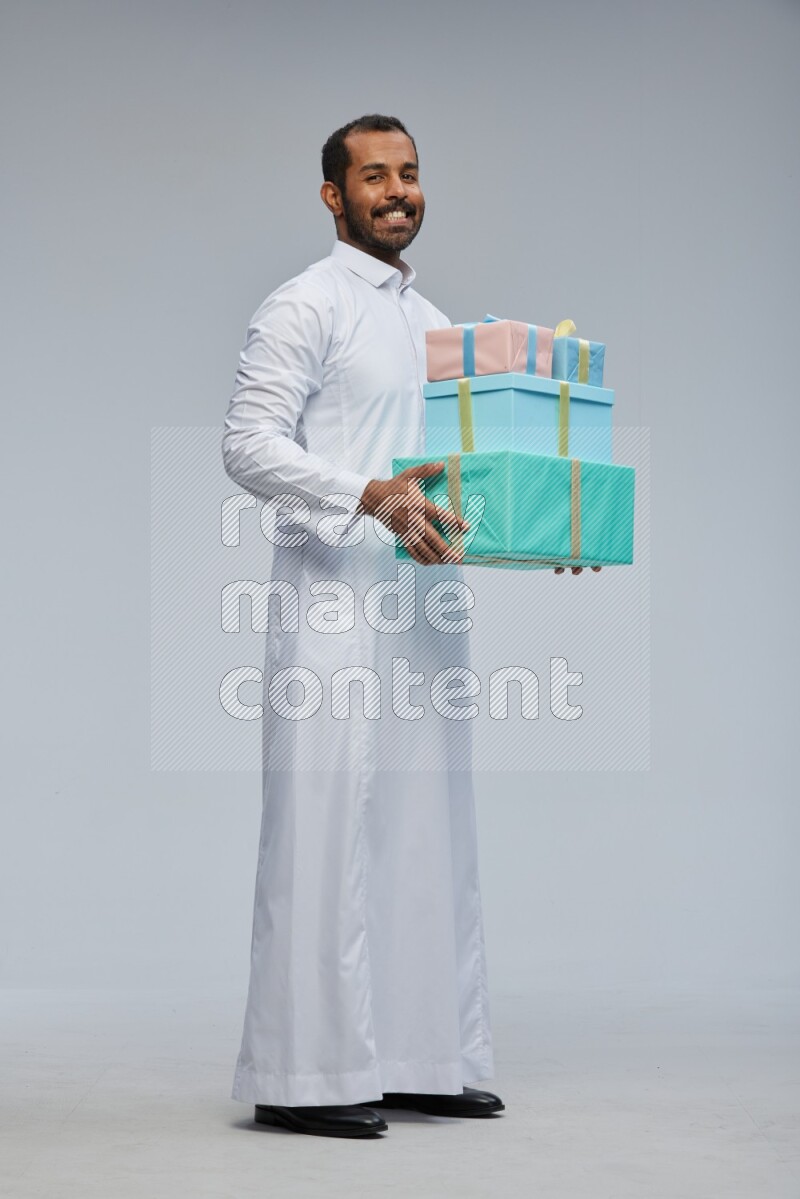 Saudi man Wearing thob standing holding gift box on Gray background