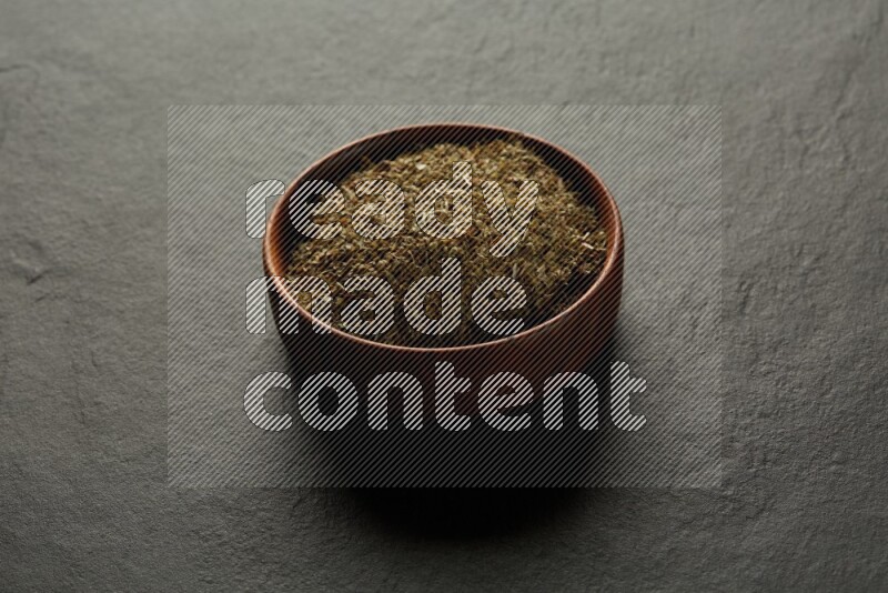 wooden round sauce bowl filled with herbs on grey textured countertop